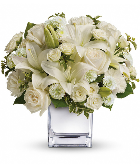 White roses, lilies and other favorites are displayed in a clear cube.